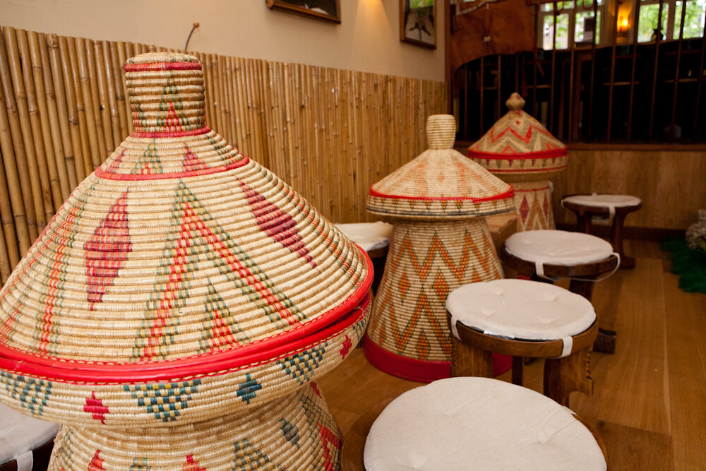 Gevlochten mesob-manden en lage krukjes in het restaurant