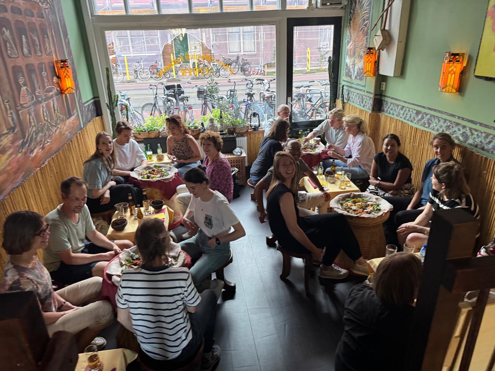 Een volle tafel gasten deelt schalen met enjera in Restaurant Semhar